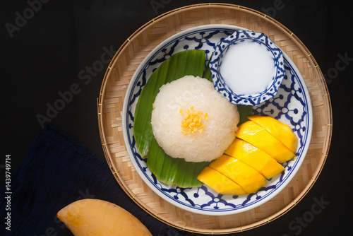 Food concept Thai authentic dessert Mango sticky rice classic Thai dessert on the ceramic plate on black background with copy space