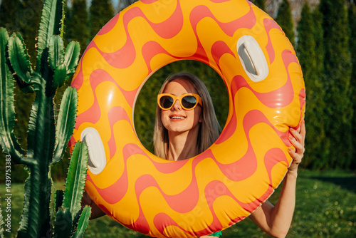 Stylish woman on vacation with inflatable ring and sunglasses outdoors