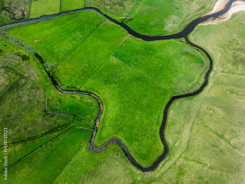 Gewundener Fluss durch grüne Felder aus der Vogelperspektive photo