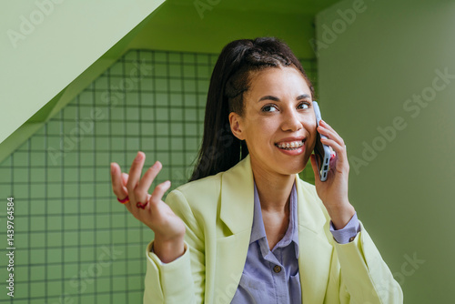 Smiling woman in business attire talking on a phone indoors
