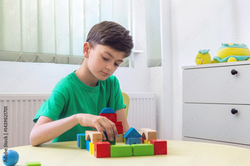 Little boy playing with colorful wooden blocks at children's therapy table, focusing on early childhood development, autism spectrum, ADHD, speech therapy, psychological support, and mental health. Little boy playing with colorful wooden blocks at children's therapy table, focusing on early childhood development, autism spectrum, ADHD, speech therapy, psychological support, and mental health.