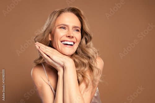 Beautiful mature woman radiating vitality and charm with elegant style and blonde hair on a beige background