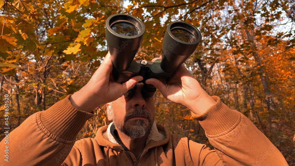 Amateur birdwatcher observing birds and other animals in nature with binoculars.