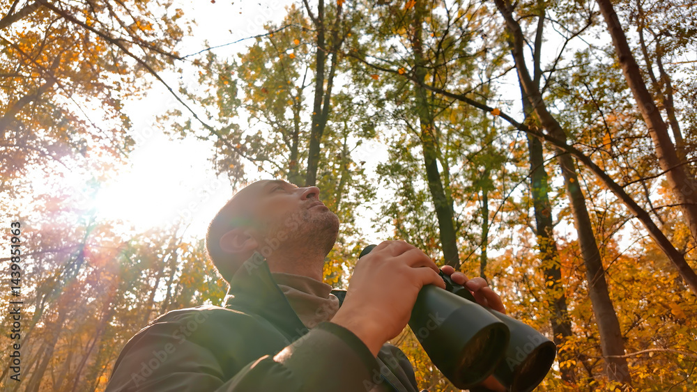 Amateur birdwatcher observing birds and other animals in nature with binoculars.