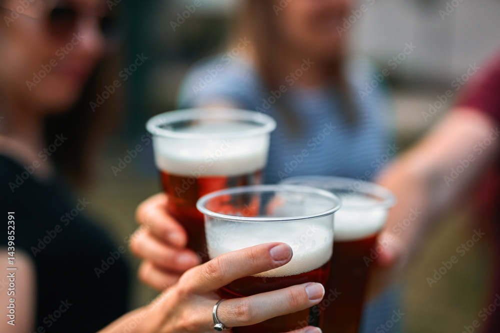 People holding beer cups and enjoying summertime outdoors.