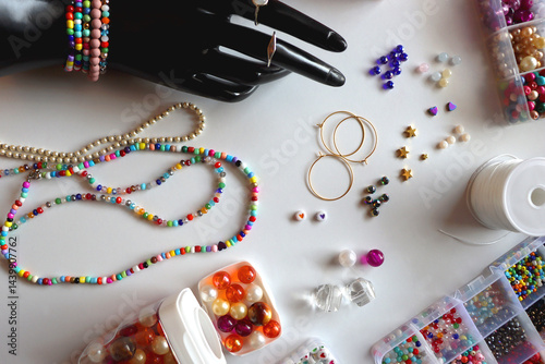 Obraz na płótnie Hand figurine, colorful friendship bracelets, necklaces, various beads and DIY supplies on the table. Making jewelry at home. Flat lay. w salonie