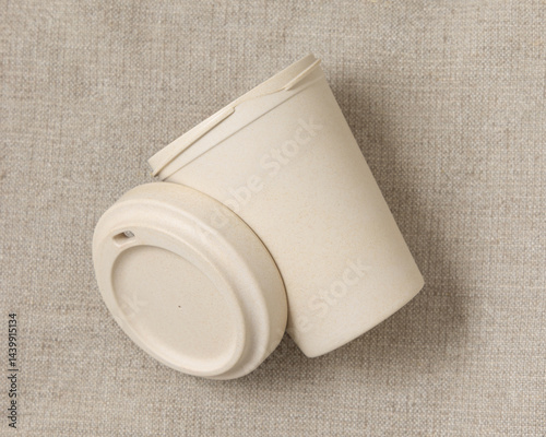 Obraz na płótnie Opened beige reusable bamboo coffee cup on beige linen cloth top view, copy space, mockup w salonie