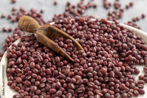 Obraz na płótnie Plate full of dried red azuki beans with a wooden scoop closeup. East Asian legumes, vegetarian food w salonie