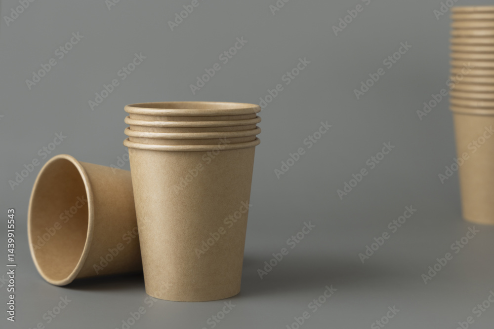 Disposable beige kraft paper cups on a gray closeup, mockup. No plastic and sustainable lifestyle