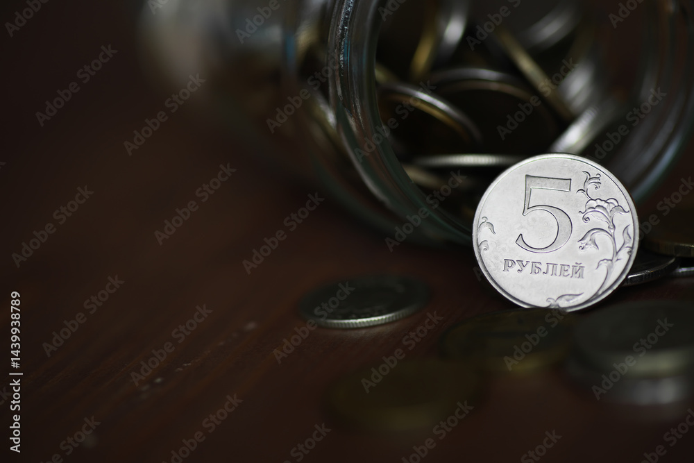 Russian 5 Ruble Coin Spilling from a Glass Jar with Multiple Coins on Wooden Surface