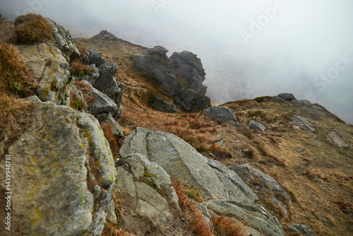 Fog envelops rocky terrain in a remote mountain landscape during a calm day in autumn. Autumn hiking in Carpathian Mountains, Ukraine