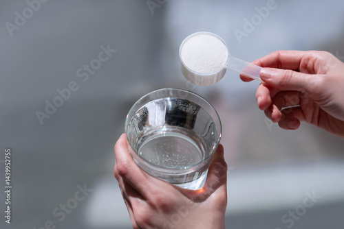 Woman hands with a scoop with collagen or protein powder and a glass of water. Trendy beauty supplement for healthy skin and bones.