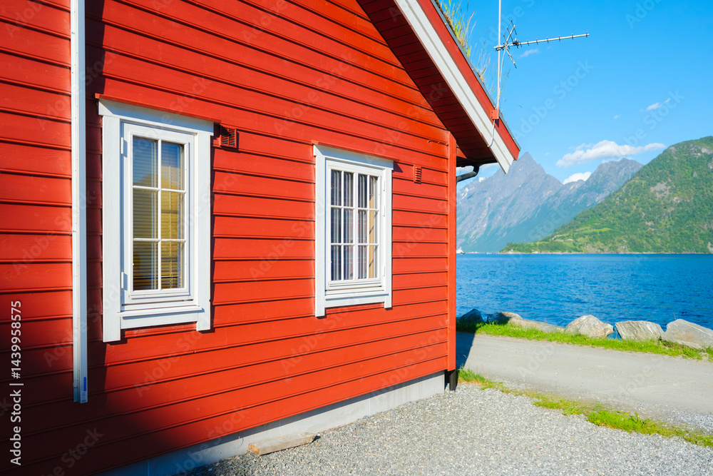 Traditional Scandinavian red houses. Beautiful mountain lake in Norway. Nature in the fjords. Vacation and travel in summer Norway. Wallpaper, postcard, background.
