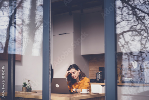Obraz na płótnie Serious thoughtful sad woman sitting at home working on laptop w salonie