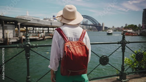 A female tourist stands in Sydney s city center with the iconic Harbour Bridge and sparkling bay as her backdrop. Smiling near the ferry wharf, she embodies summer joy in Australia