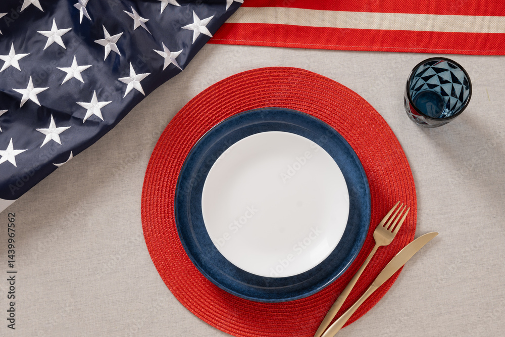 Festive table setting for American Independence Day. Holiday dinner with empty white plate and decoration in USA national flag colors white, red and blue. View from above. Copy space. Close up.