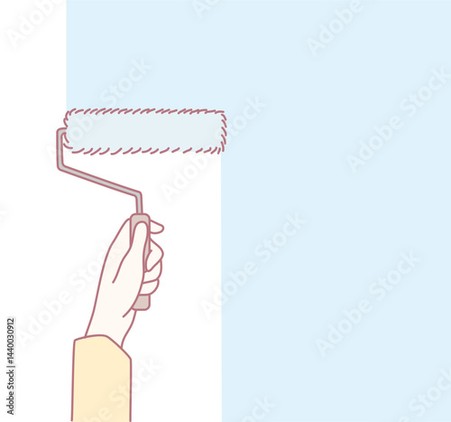 A hand skillfully using a paint roller to apply a light shade of blue paint on a wall, enhancing home decor