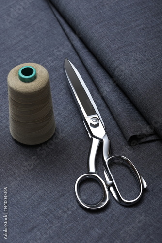 Professional sewing scissors rest atop a bolt of deep blue denim fabric, representing craftsmanship, fashion tailoring, and precision in garment-making. 