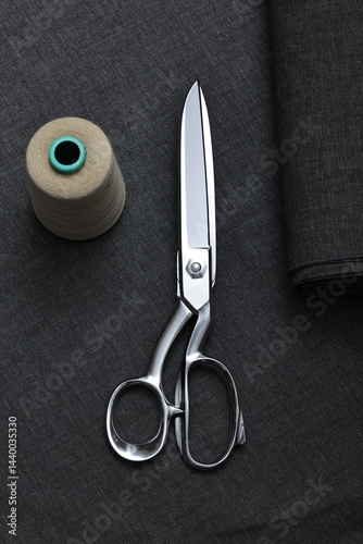 Professional sewing scissors rest atop a bolt of deep blue denim fabric, representing craftsmanship, fashion tailoring, and precision in garment-making.