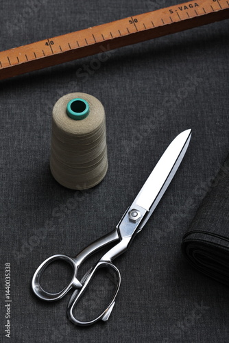 Professional sewing scissors rest atop a bolt of deep blue denim fabric, representing craftsmanship, fashion tailoring, and precision in garment-making.