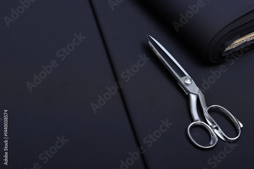 Professional sewing scissors rest atop a bolt of deep blue denim fabric, representing craftsmanship, fashion tailoring, and precision in garment-making.