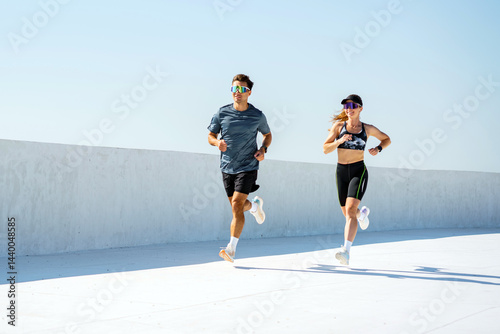 Obraz na płótnie Runners sprinting along a bright, modern track under a clear blue sky at midday
