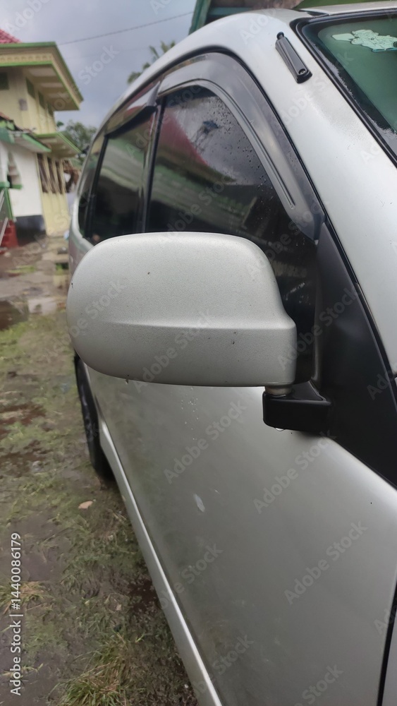 Fototapeta premium Silver car side mirror gleaming subtly reflecting a rainy day vibe pure automotive elegance