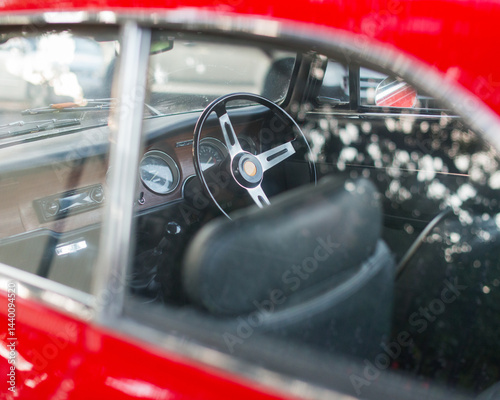 A three spoke steering wheel inside a shiny red car
