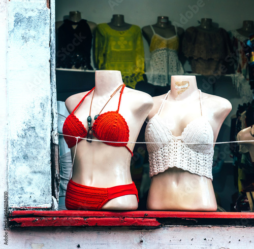 Brightly colored swimsuits displayed in a shop window in a coastal town during a sunny afternoon