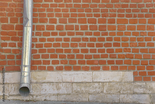 Brick wall with a drain pipe to drain rainwater from the roof. The pipe is attached to the wall.