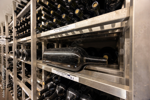 Large wine bottle lying down aging in metal shelves in winery cellar