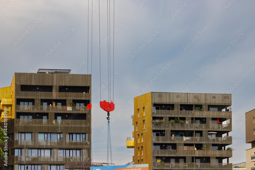 Crane lifting building materials in urban construction site with modern buildings