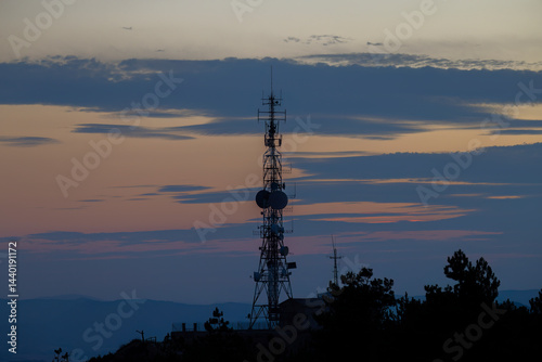 Obraz na płótnie Telecommunication tower silhouette at sunset illuminating colorful clouds w salonie