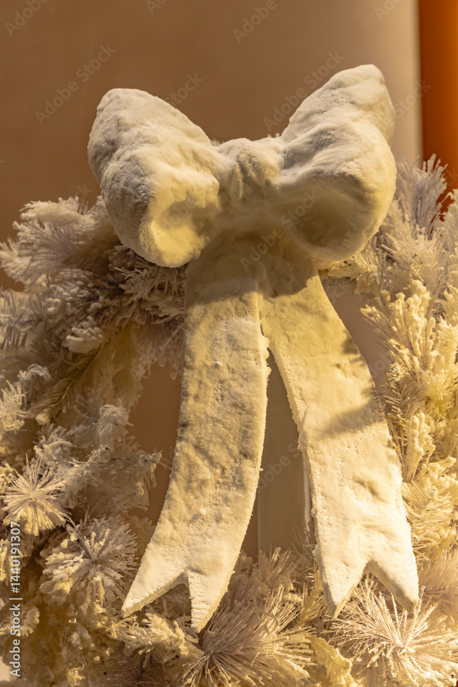 Large white christmas bow decorating a snowy wreath