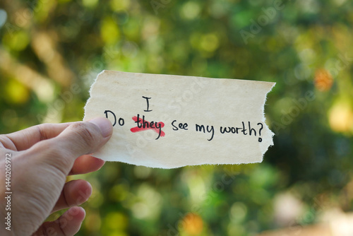 hand holding a note paper with the words Do They See My Worth? replacing Do I See My Worth? Self-Reflection, Identity, Empowerment, Emotional Growth, Mental Health Journey