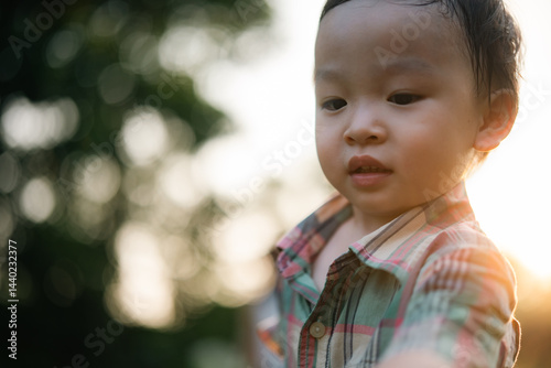 Adorable young boy enjoying outdoor sunshine with happy expression and natural bokeh background symbolizing innocence childhood freedom happiness and carefree exploration moments