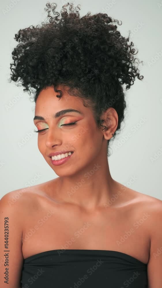 Vertical portrait of young smiling model with curly hair in afro style and bright makeup Vertical portrait of young smiling model with curly hair in afro style and bright makeup