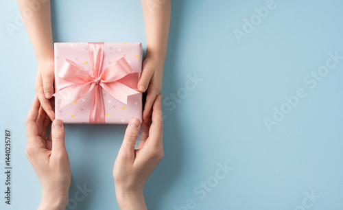 A pair of hands offers a wrapped gift to another set of hands, conveying affection