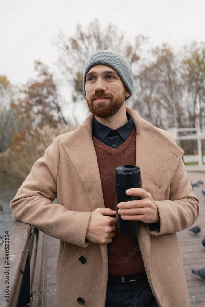 Man enjoying a hot drink while standing outdoors wearing warm clothing
