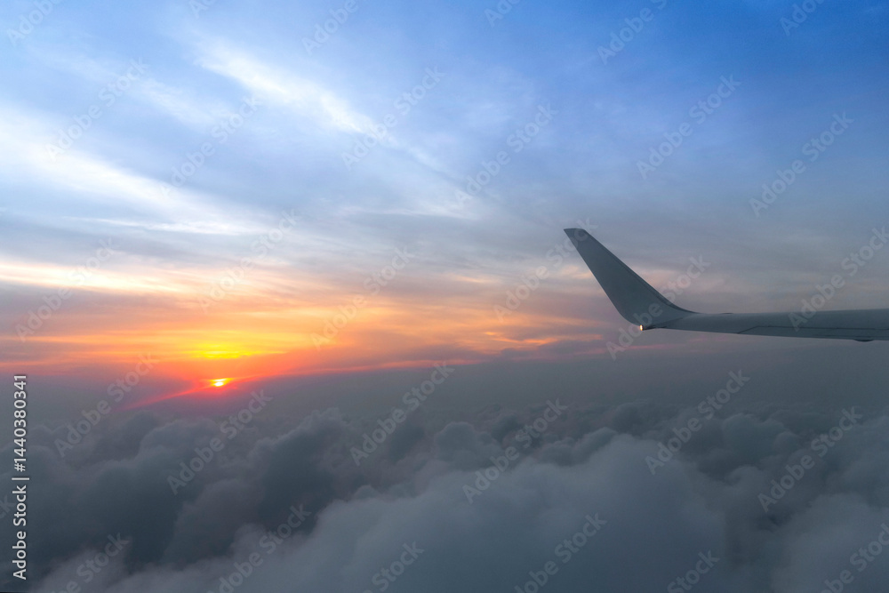 Wing of the air plane on the sea of cloud sunset sky background from window airplane