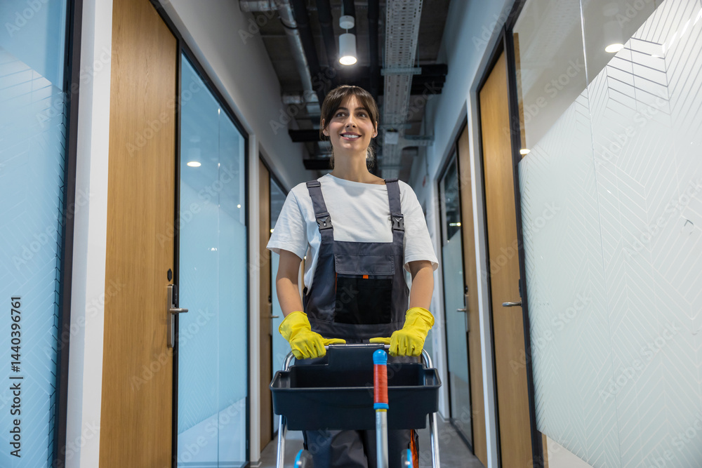 Dark-haired young woman in uniform with a cart of cleaning equipment Dark-haired young woman in uniform with a cart of cleaning equipment