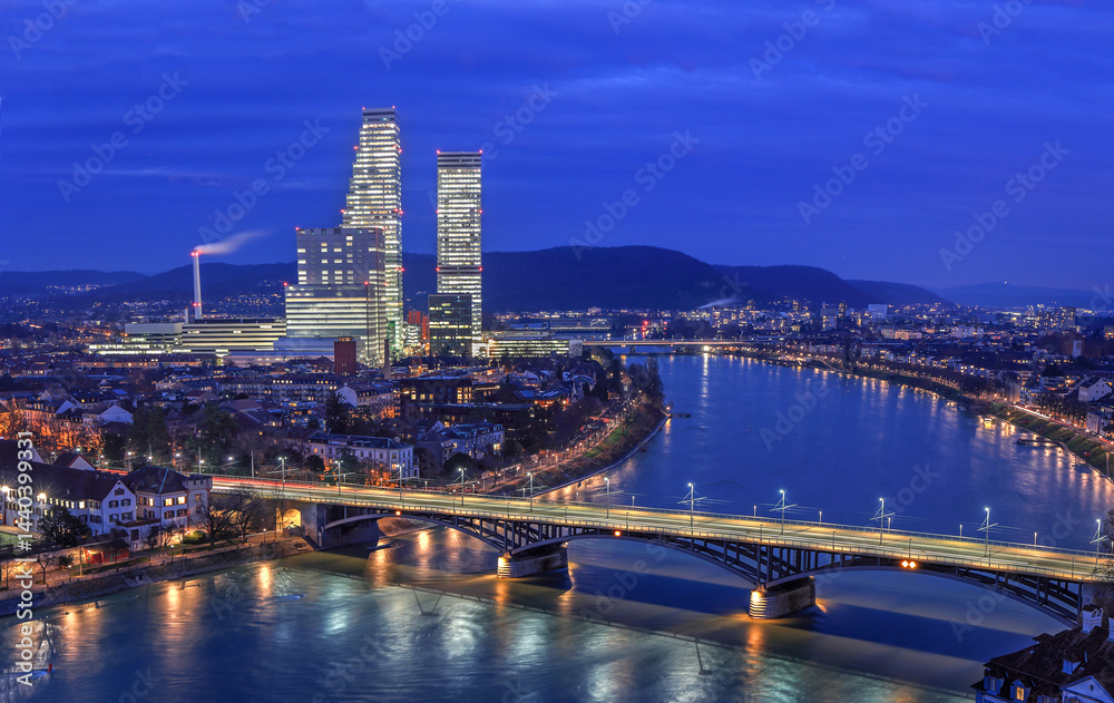 Night cityscape of the Swiss city Basel over the Rhine river with street lights and high rise buildings Night cityscape of the Swiss city Basel over the Rhine river with street lights and high rise buildings