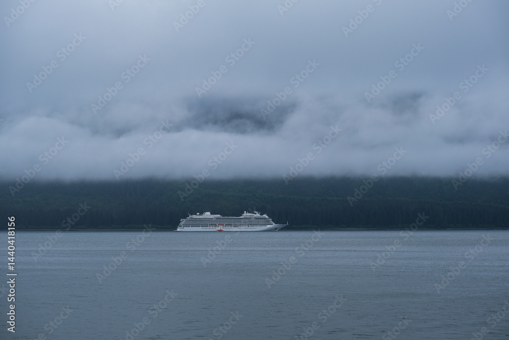 Luxury cruiseship cruise ship liner Orion and kayaks boat in Hoonah Icy Strait Point Bay, Alaska with low hanging clouds and nature landscape scenery