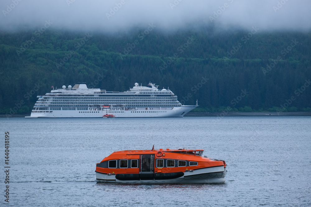 Luxury cruiseship cruise ship liner Orion and kayaks boat in Hoonah Icy Strait Point Bay, Alaska with low hanging clouds and nature landscape scenery