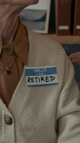 Vertical closeup of unrecognizable office colleague gently pinning Retired badge onto senior woman sweater, marking her transition and celebrating her career