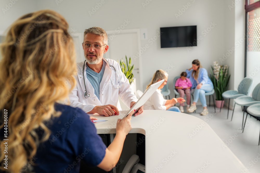 Obraz premium Doctor and nurse are discussing patient information using a tablet at the reception desk of a modern clinic, while patients are waiting in the background