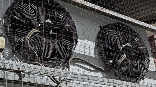Outdoor unit of the air conditioner behind a metal mesh