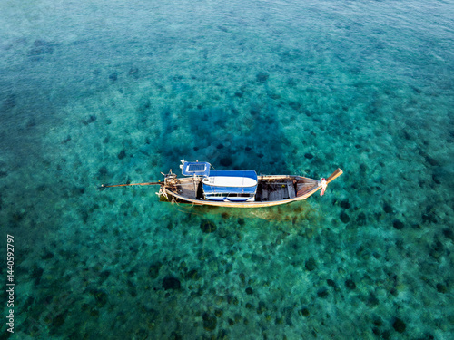 Drone shot of a traditional Thai longtail boat floating on clear turquoise waters in Thailand.