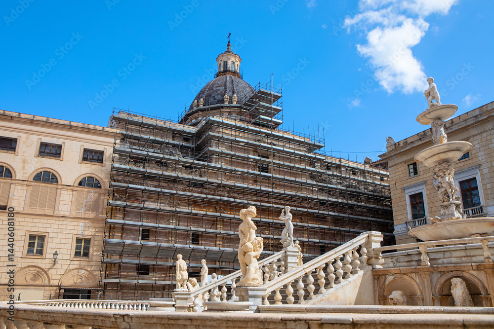 Historic Piazza Pretoria in Palermo, Sicily, featuring the famous Fountain of Shame and a dome under restoration, with scaffolding against a bright blue sky and elegant marble statues in foreground