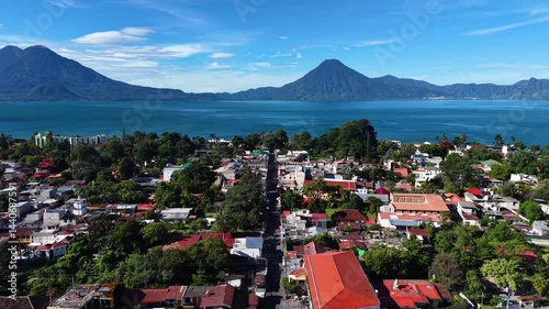 Beautiful cinematic aerial view os the Panajachel town surrounded by Toliman and Atitlan volcanoes, next to the Atitlan lake its piers and traditional fisher and tourist boats - Guatemala